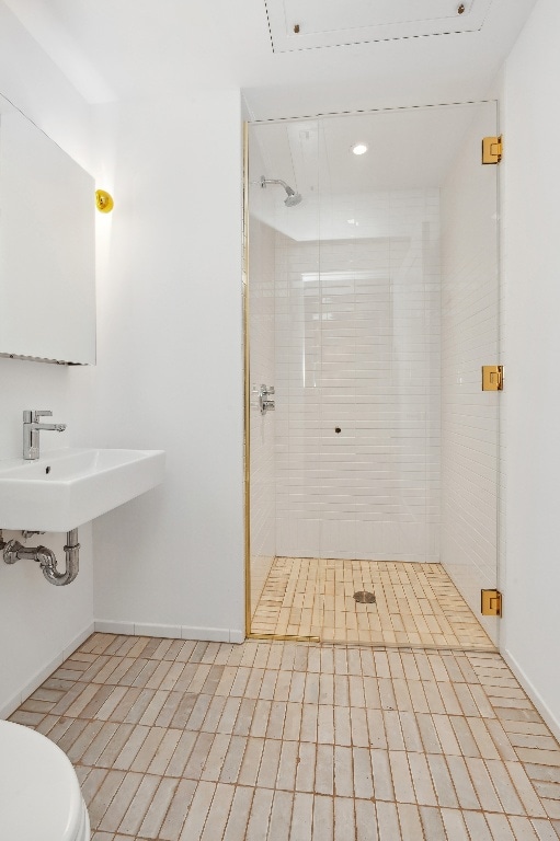 bathroom featuring tiled shower, toilet, tile patterned flooring, and sink