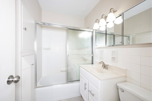 full bathroom featuring toilet, decorative backsplash, tile walls, vanity, and shower / bath combination with glass door