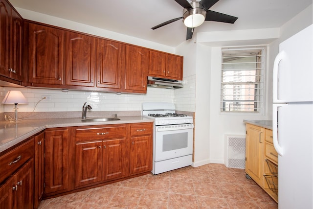 kitchen featuring under cabinet range hood, white appliances, a sink, visible vents, and backsplash