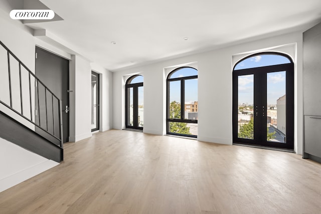 entrance foyer with light wood-type flooring, stairway, and baseboards