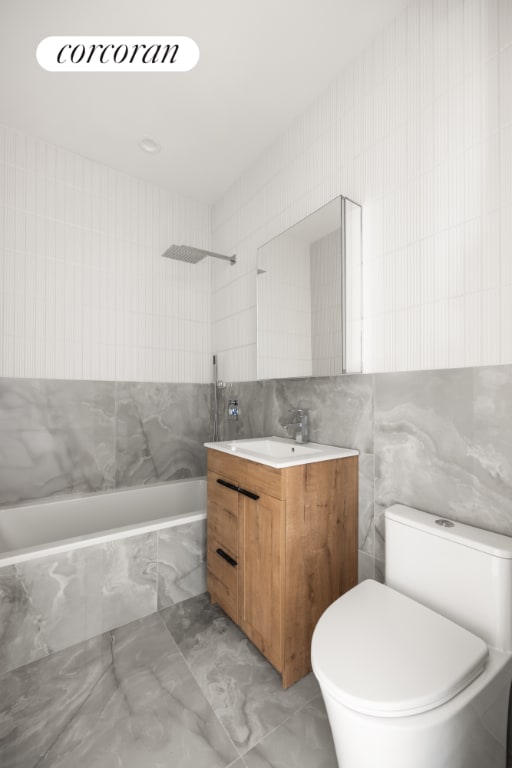 full bathroom featuring toilet, tile walls, tiled shower / bath, and vanity