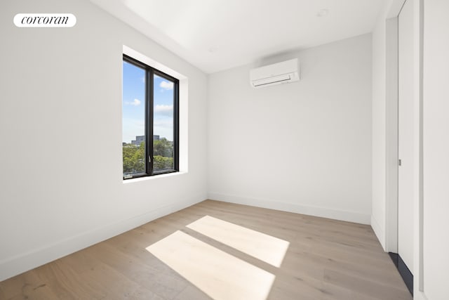 empty room with light wood-type flooring and a wall mounted AC