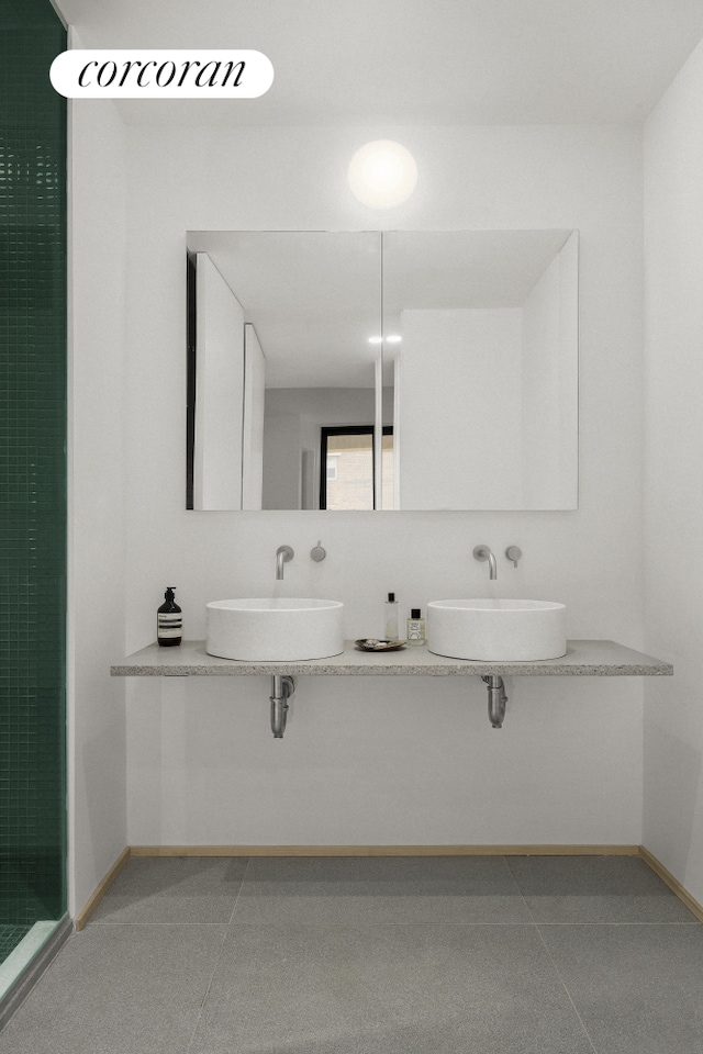 full bath featuring tile patterned floors, double sink, a shower stall, and baseboards