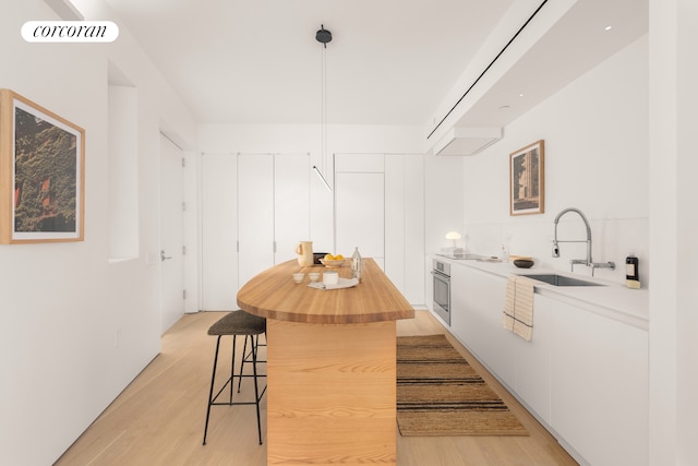 kitchen with visible vents, white cabinets, light countertops, pendant lighting, and a sink