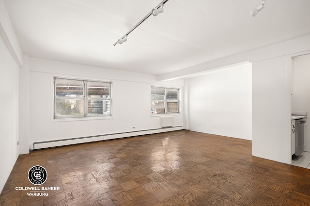 spare room featuring a baseboard heating unit, track lighting, and parquet flooring