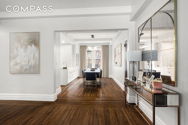 hall with a sink, baseboards, and dark wood-style floors