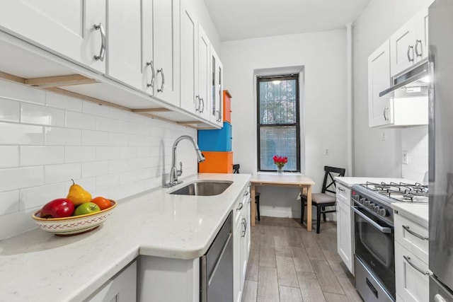 kitchen featuring tasteful backsplash, sink, white cabinets, stainless steel appliances, and light hardwood / wood-style flooring