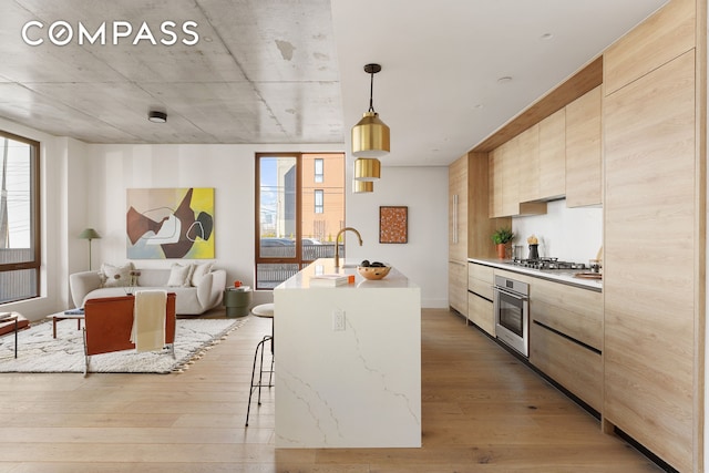 kitchen with stainless steel appliances, light wood-style floors, a kitchen bar, and modern cabinets