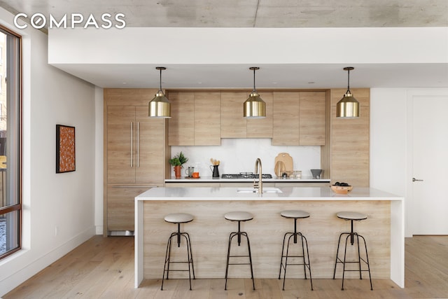 kitchen with light brown cabinetry, a breakfast bar area, light wood-type flooring, and light countertops