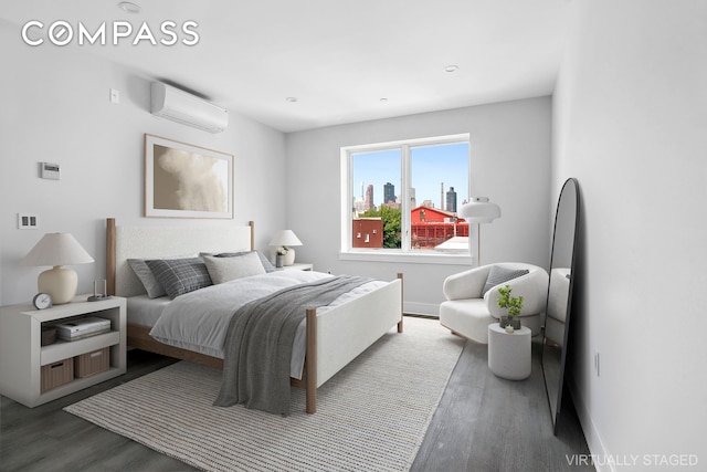 bedroom with an AC wall unit, a city view, baseboards, and wood finished floors