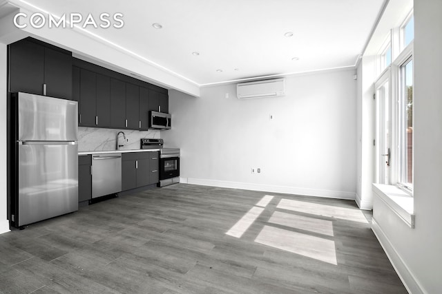 kitchen with tasteful backsplash, appliances with stainless steel finishes, light countertops, dark cabinetry, and an AC wall unit