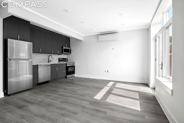 kitchen featuring sink, a wall mounted air conditioner, stainless steel appliances, light hardwood / wood-style floors, and decorative backsplash