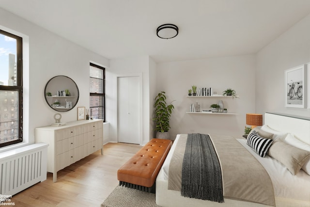 bedroom featuring light wood-style floors, multiple windows, and radiator heating unit