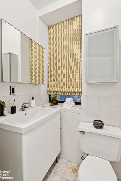 bathroom with vanity, toilet, and tile walls