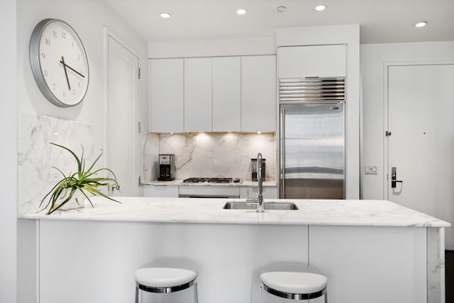 kitchen with stainless steel appliances, white cabinets, a sink, and decorative backsplash