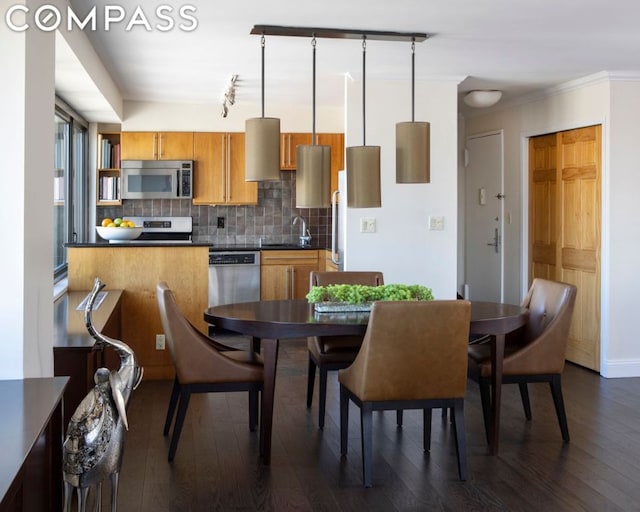 dining area featuring dark hardwood / wood-style floors, sink, ornamental molding, and rail lighting