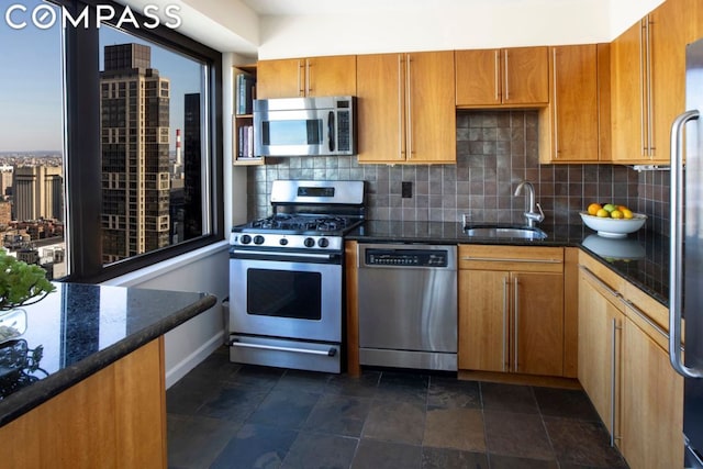 kitchen featuring appliances with stainless steel finishes, dark stone countertops, tasteful backsplash, and sink