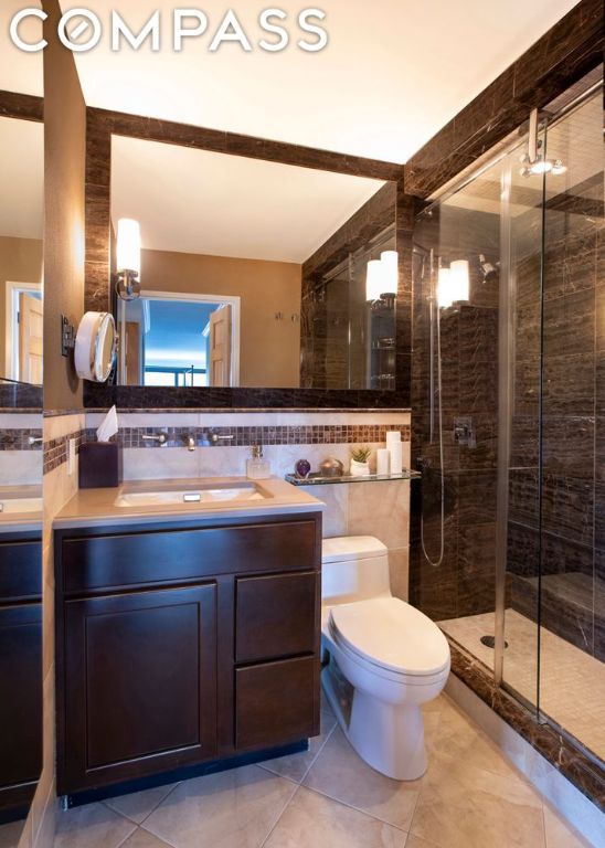 bathroom with toilet, tile patterned flooring, tile walls, an enclosed shower, and vanity