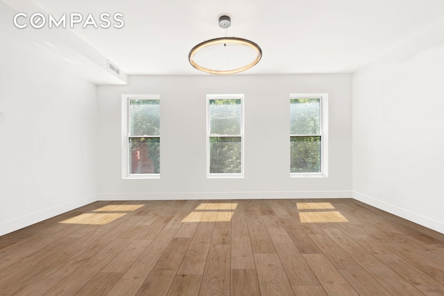 empty room with visible vents, baseboards, and wood-type flooring