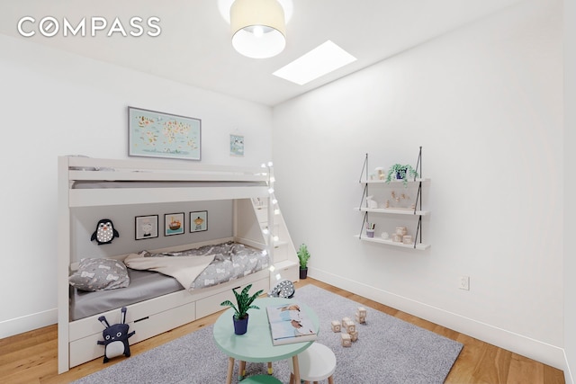 living room featuring baseboards, wood finished floors, and a skylight