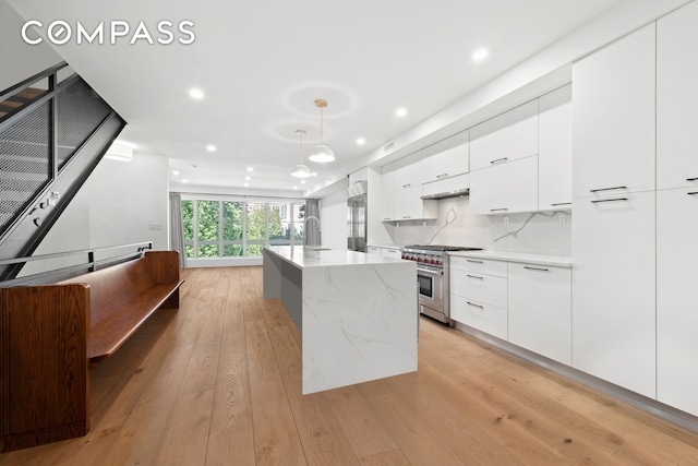 kitchen featuring premium appliances, white cabinetry, modern cabinets, and light wood-style floors