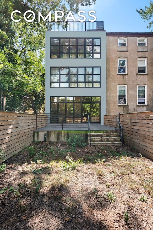 rear view of property featuring stucco siding and fence