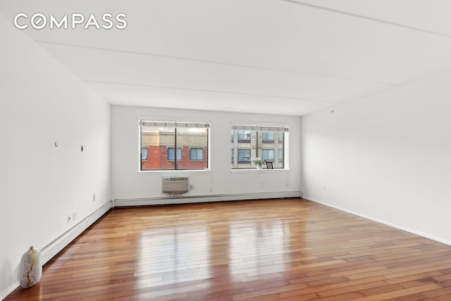 empty room featuring a wall unit AC, light wood-style floors, a baseboard radiator, and a baseboard heating unit