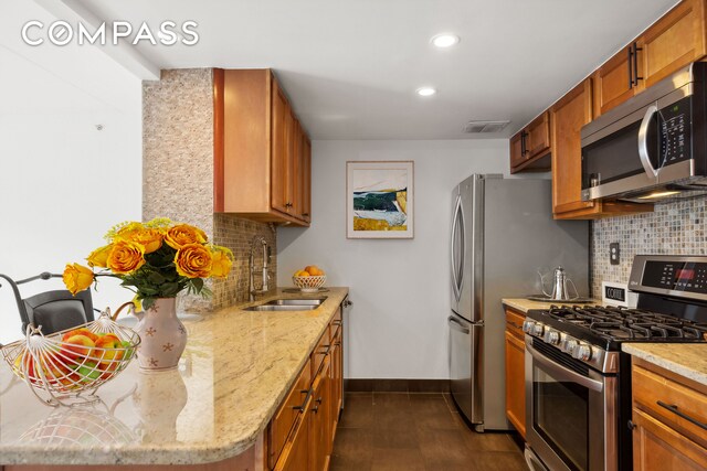 kitchen with baseboards, visible vents, a sink, stainless steel appliances, and brown cabinets