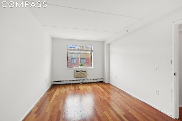 empty room featuring a wall mounted air conditioner, a baseboard radiator, and wood-type flooring