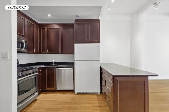 kitchen featuring sink, track lighting, kitchen peninsula, stainless steel appliances, and light hardwood / wood-style floors