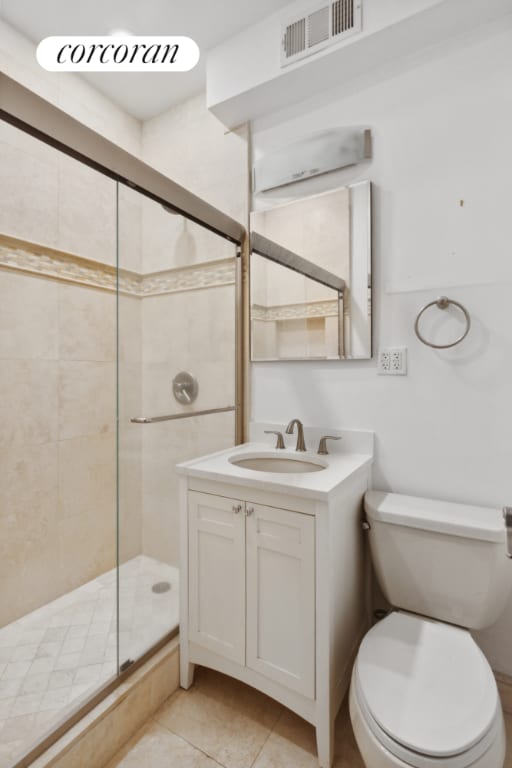 bathroom featuring vanity, toilet, tile patterned flooring, and a shower with door