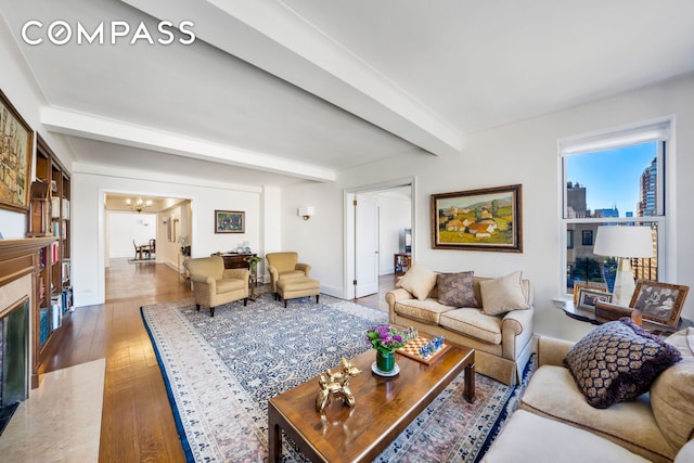 living room with hardwood / wood-style flooring, a high end fireplace, beam ceiling, and an inviting chandelier