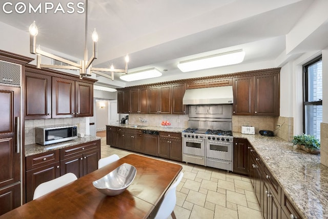 kitchen featuring light stone countertops, backsplash, hanging light fixtures, and appliances with stainless steel finishes