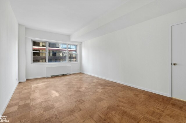 spare room with radiator and light parquet floors