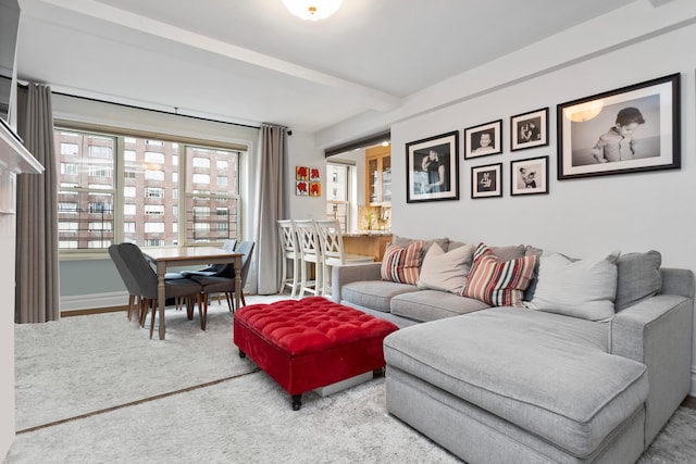 carpeted living area with beamed ceiling