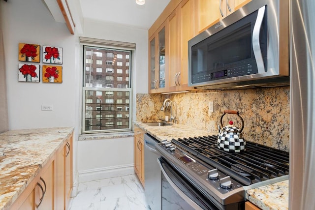 kitchen featuring light stone counters, sink, tasteful backsplash, and stainless steel appliances