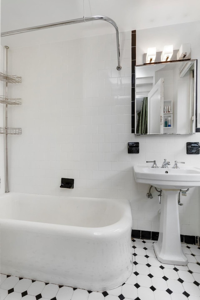 bathroom featuring a tub, tile walls, decorative backsplash, and a sink