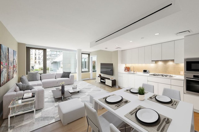 living room featuring plenty of natural light, sink, and light hardwood / wood-style floors