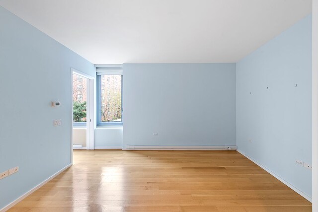 425 W 53rd St Unit 301, New York City, NY 10019 - empty room with light wood-type flooring, baseboards, and a baseboard heating unit