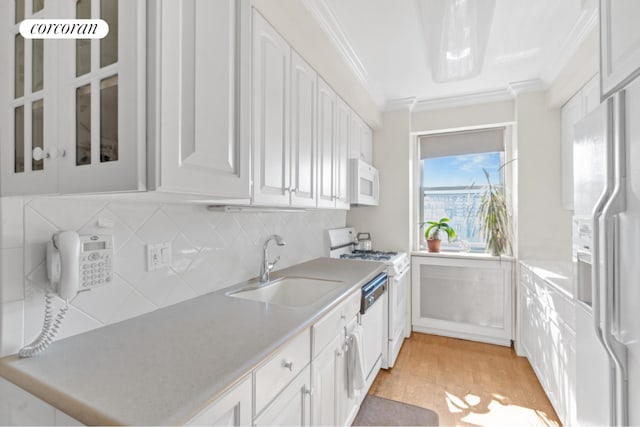 kitchen featuring white appliances, white cabinetry, sink, ornamental molding, and light wood-type flooring