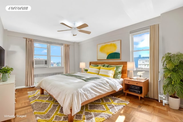 bedroom with radiator, ceiling fan, cooling unit, and multiple windows