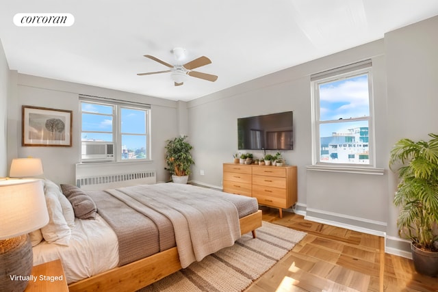 bedroom with ceiling fan, radiator, cooling unit, and light parquet floors