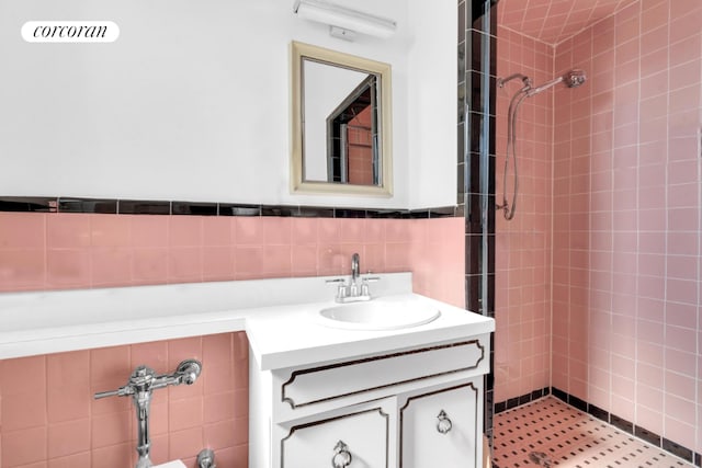 bathroom with tile walls, tiled shower, and vanity