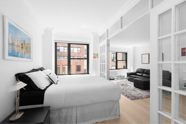 bedroom with crown molding and wood finished floors