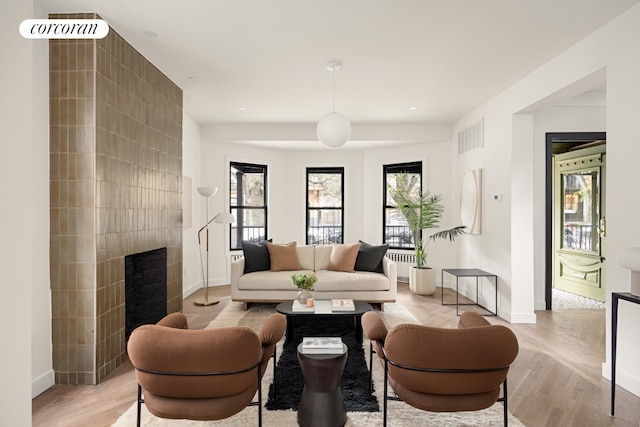 living room with a tiled fireplace and light hardwood / wood-style floors