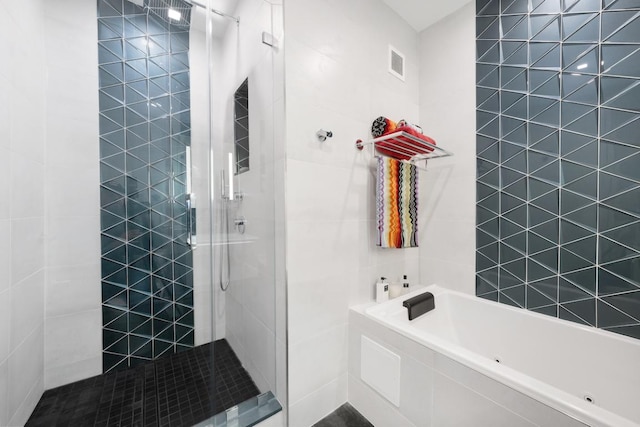 bathroom with tile walls and shower with separate bathtub