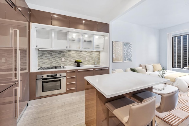 kitchen with a breakfast bar, decorative backsplash, sink, appliances with stainless steel finishes, and white cabinets