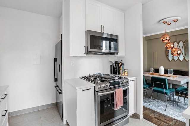 kitchen featuring stainless steel appliances, baseboards, white cabinets, hanging light fixtures, and light countertops