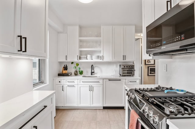 kitchen with light tile patterned floors, appliances with stainless steel finishes, sink, and white cabinetry