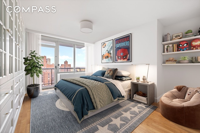 bedroom with a view of city, access to outside, and light wood finished floors